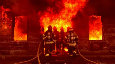 Firefighters battle intense flames engulfing a residential house on South Hanover Street at night.