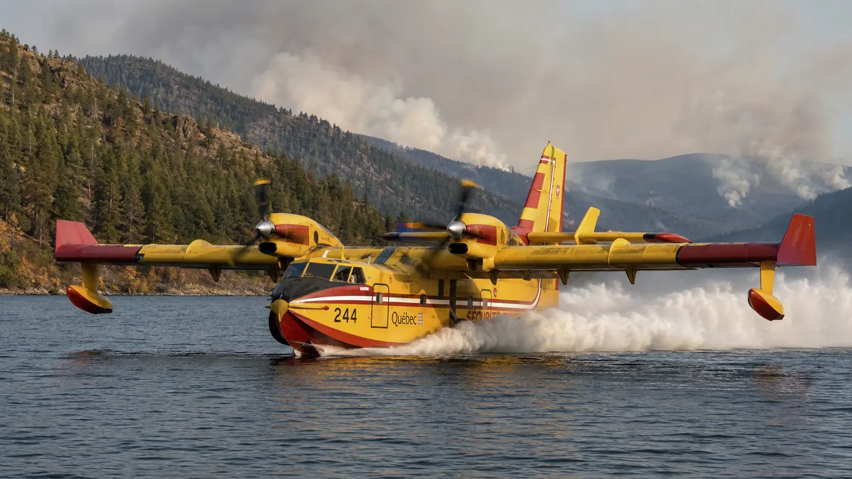 Amphibious firefighting aircraft skimming a lake to collect water for an aerial drop.