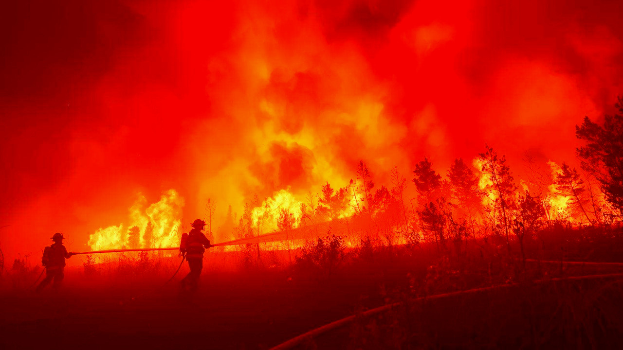 Firefighters battle intense flames amid smoky skies during Los Angeles wildfire disaster.