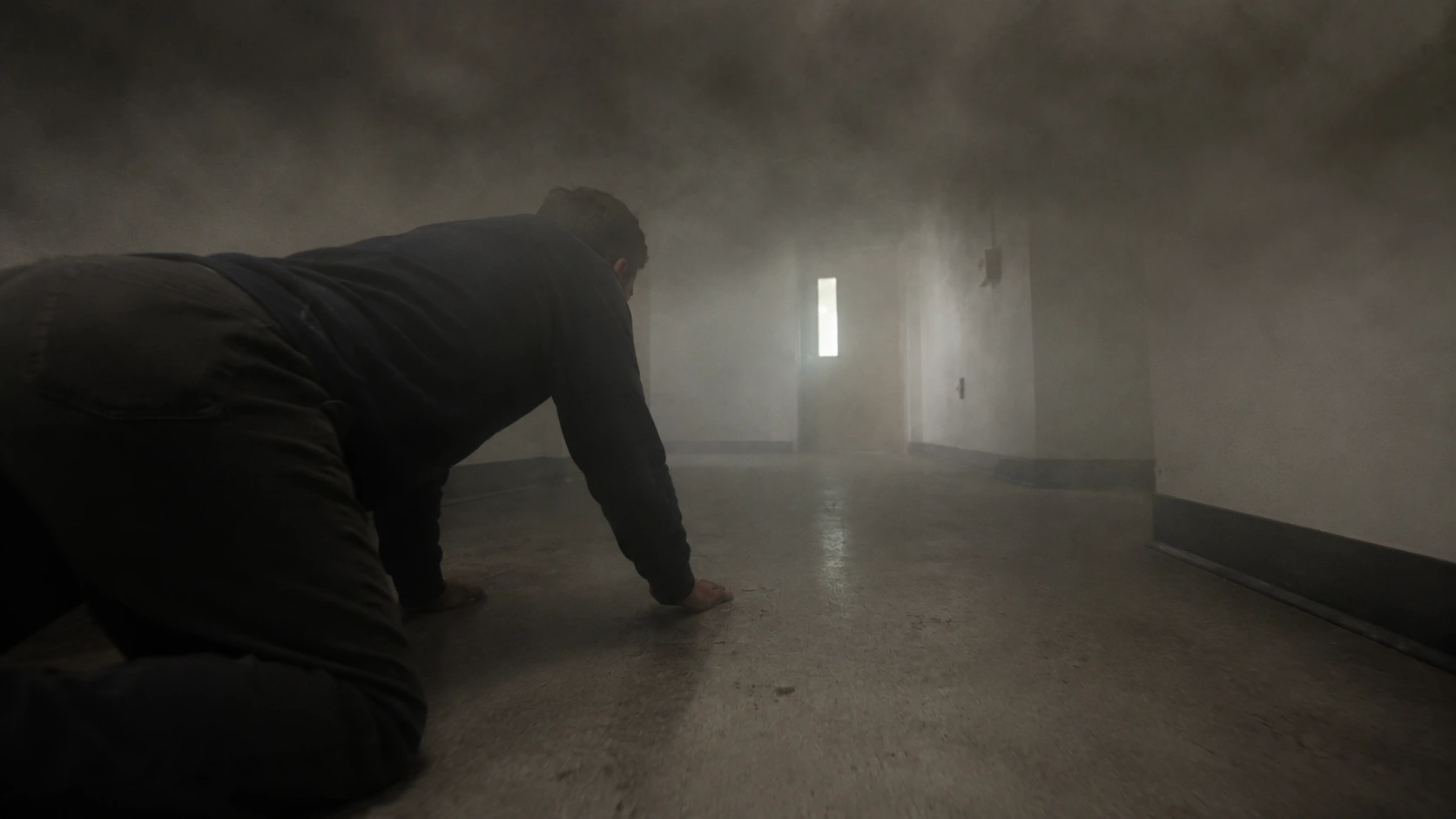 Person demonstrating correct low crawl position close to floor in smoke-filled corridor during fire survival &mdash; staying below toxic smoke layer