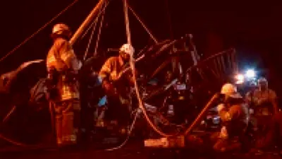 Firefighter being rescued from a blazing furniture store in downtown Chicago, surrounded by thick smoke and flames.