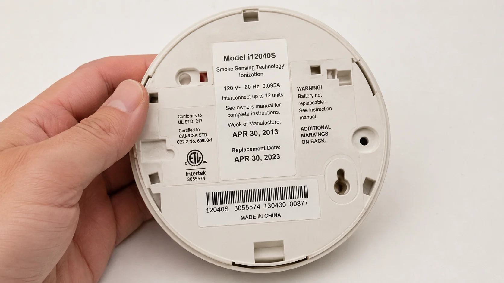 Back of smoke alarm showing manufacture date label, demonstrating how to check if alarm is past its 10-year service life and needs replacement