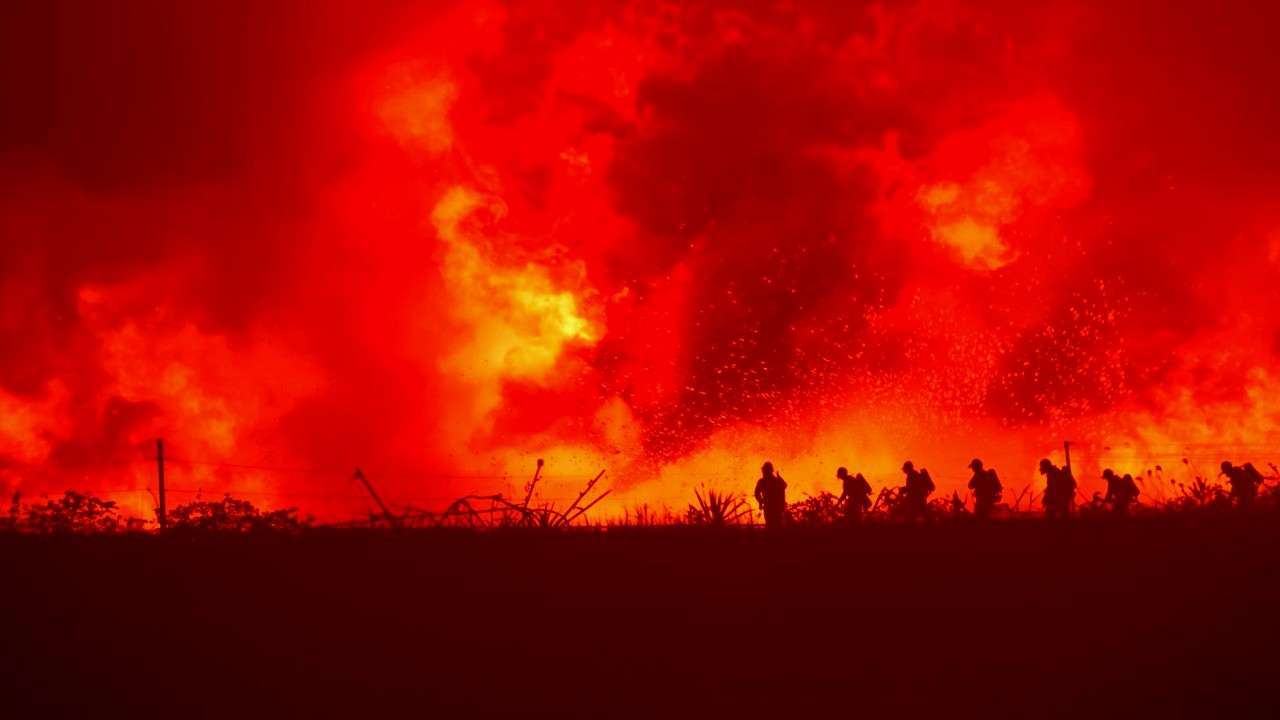 Firefighters battle intense flames amid dense forest smoke during the Lower Sugarloaf wildfire in Washington state.